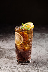 Dark cocktail with cola and oranges on black background