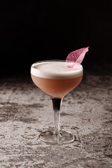 Pink alcoholic cocktail in high glass on black background