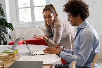 Two casually dressed coworkers discussing ideas at the office for a new startup project.	

