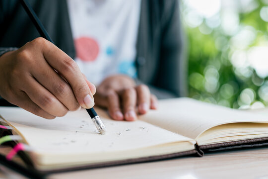 Close up of college student hands erase mistake on notebook.