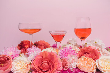 Fun, colorful floral summer arrangement with three wine and cocktail glasses and pink and red flowers. Bright and trendy feminine concept.