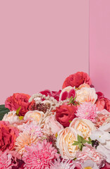 Bunch of pink and red spring flowers on pastel pink background. Bright and trendy feminine aesthetic with copy space.