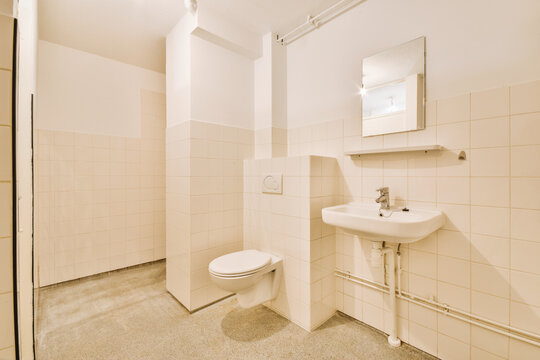Old sink with mirror near toilet in light bathroom