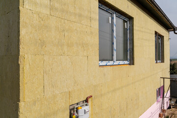 Layer of thermal insulation on the wall of the house outside. Mineral wool panels. - obrazy, fototapety, plakaty