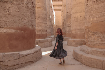 Woman between the pillars in the temple of Karnak in Luxor. - obrazy, fototapety, plakaty