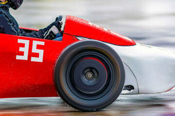 Racing cart in selective focus driving on an empty wet rainy road or track at high speed - motion...