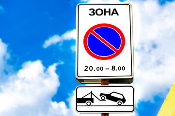 Road sign - no parking. Cloudy sky background.  There is an inscription: 