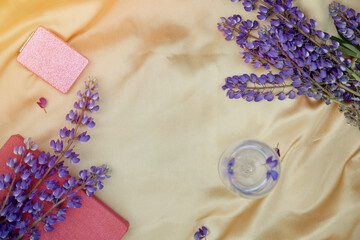 Lupins purple flowers and wine glass decorations on golden background. Concept of summer invitation, birthday card, Mother's day. Place for text. Wellness closeness to nature, self-discovery concept.