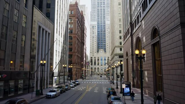 Black lampposts as street lighting in S LaSalle street with the high and well-known Chicago Board of Trade building in the background. Drone dolley shot between the skyscrapers.