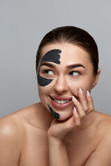 Beautiful young woman with black mask of clay on face clean fresh skin . Girl beauty face care. Facial treatment . Purifying Moisturizer mask