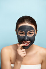 Beauty Woman Face Skin Care Mask. Portrait of a Beautiful Female with a Black Mask of Clay on Face .  Spa treatment . Girl Model with Moisturizer Cosmetic Mask.