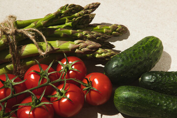 Set of fresh vegetables, asparagus, tomatoes, cabbage and cucumbers on a beige background