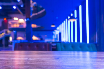 Selective focus on the table board of a restaurant nightclub modern design background in neon blue light