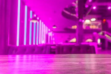 Selective focus on the table board of a restaurant nightclub modern design background in neon purple light