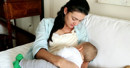Obraz premium Casual mother breastfeeding baby infant son in living-room sofa