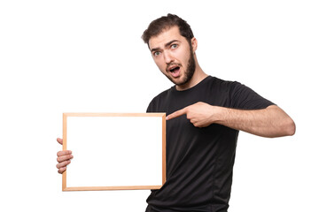 Look over there! Surprised guy with open mouth points finger space for your text or ad on poster. Man in black t-shirt shows advertisement in studio. Isolated on white background