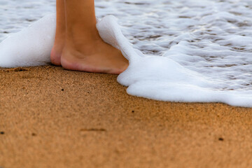 sea wave covering feet on the beach shore