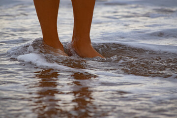 feet bathed in the sea water on the shore of the beach