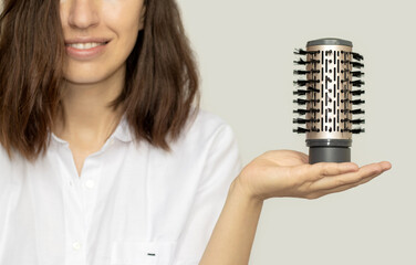 young woman holding in hand a modern rotative hair brush head. style hair.smiling girl,close up.hair dryer and volumizer,hot,cold air. hermal and ceramic coating of dryer.