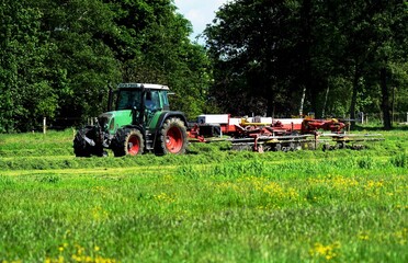 Tractor with tedder in may under blue sky