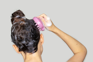 hair growth stimulating, scalp massage.woman using  pink scalp massager shampoo brush with silicone,flexible bristels.hair care,head relaxation.shampoo foam on hair,hand,isolated - obrazy, fototapety, plakaty
