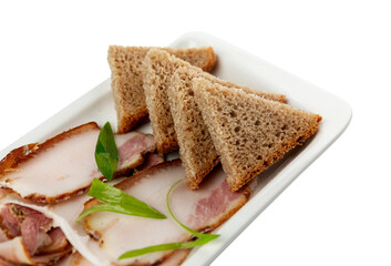 Appetizing pieces of lard with brown bread on a plate. Traditional Russian and Ukrainian snack. Close-up. Isolated on white background.