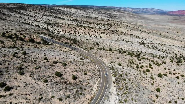 Car drives through scenic arid landscape along US Highway 89A; aerial