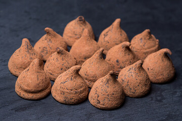 Chocolate truffle candies on a black background. Delicious chocolate dessert.