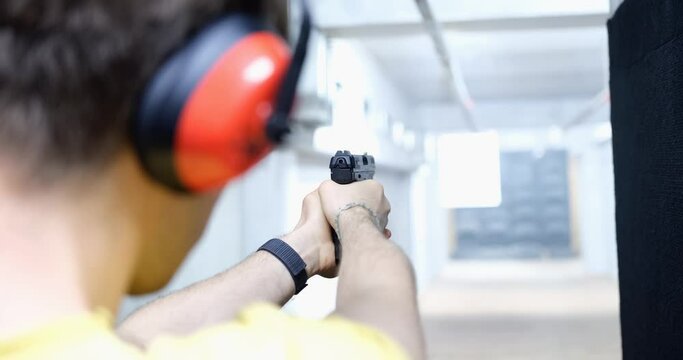 Man aims pistol at target in indoor or shooting range