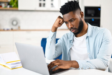 Tired multiracial businessman sitting with computer at home and has a problem with remote work....