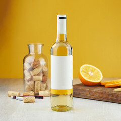 Wine bottle with blank tag jar with corks and orange on table