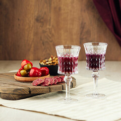Vintage wineglasses with red wine and tasty snacks on table