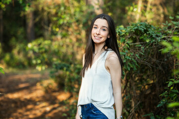 A beautiful happy teenage brunette girl outdoors in a wooded area in the spring