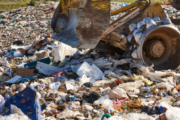 Heavy machinery shredding garbage in an open air landfill. Pollution