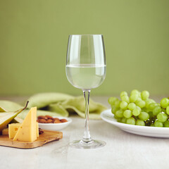 Glass of white wine with cheese and grape on table closeup