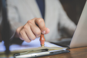 Close-up of a person's hand stamping with passed and approved stamp on certificate document public...