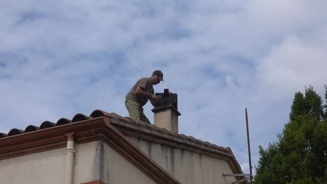 Manipulation of the fireplace chimney by a person on the roof for seasonal cleaning of soot.