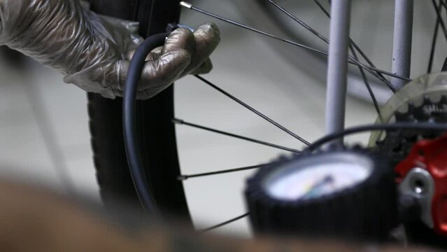 Mechanic checks pressure in wheels with help of pressure gauge pumps up wheels of bicycle. Riding flat tires contributes to deterioration in maneuverability, it is necessary monitor pressure of tires.