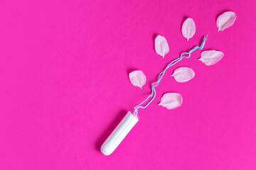 Female tampon with with cherry petals on a pink background. Hygienic white tampon for women. Cotton swab.