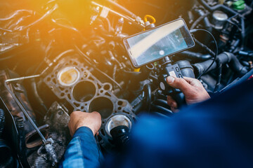 Hands of car mechanic check the vehicle engine with technical endoscope with rotary camera and...