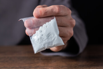 Concept drug addiction. Man hand holds plastic packet or bag with cocaine or another drugs