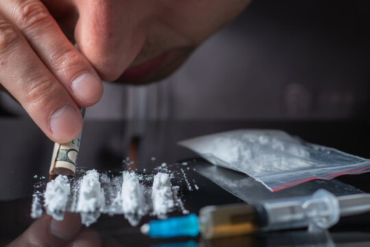 Concept drug addiction.. Drug abuse, man taking drugs, snorting lines of cocaine powder, close up