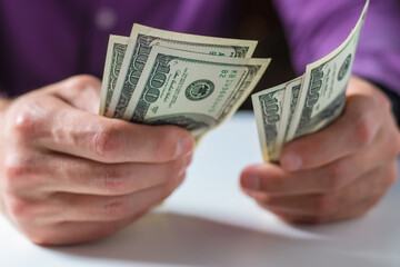 a man holds stack hundred-dollar bills in his hands close-up.