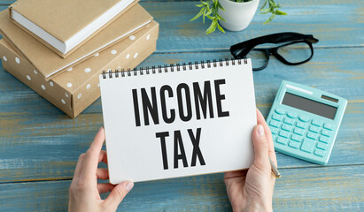 Income Tax text on paper sheet with magnifying glass on chart, dice, spectacles, pen, laptop and...