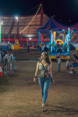 Fototapeta na wymiar AMUSEMENT PARK FULL OF LIGHTS AND COLOR WITH MECHANICAL ATTRACTIONS WOMAN ENJOYING THE PLACE