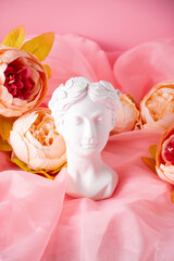 Bust of a Greek goddess on a pastel pink background. Minimal flat still life. Beauty overhead concept.
