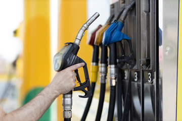Man holding filling gun in his hand at gas station. Sanctions economy crisis concept