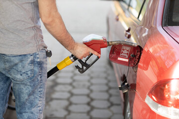 Man filling fuel tank in his hand at gas station. Sanctions economy crisis