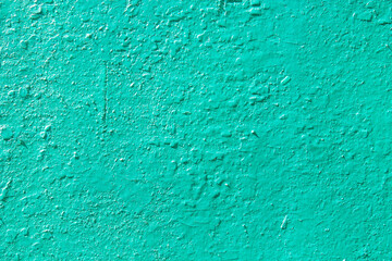 The green texture of old cracked paint. The turquoise wall is painted with paint. The background of a painted concrete wall. Industrial background