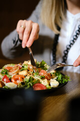 Woman's hands hold utensils in a plate
